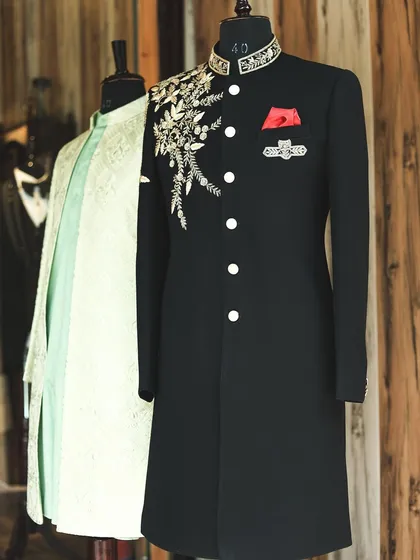 Another view from the studio, focusing on the black sherwani with its intricate gold floral embroidery. This piece is a favorite for grooms looking for a powerful and regal reception look.