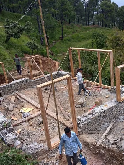 Door and window frames are carefully placed as the stone walls rise around them. This traditional construction method integrates the openings directly into the load-bearing structure, ensuring a solid and cohesive build.
