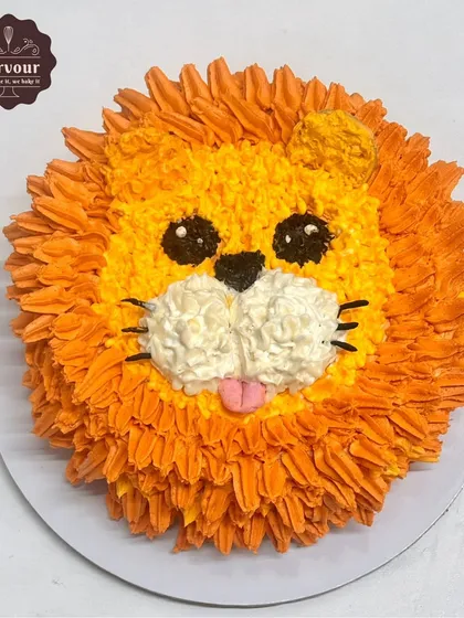 A cute and simple lion theme cake. The lion's friendly face and mane are created entirely with piped whipped cream, showing that you don't need fondant for a fun character cake.