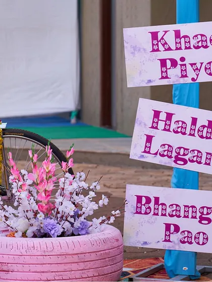 Fun and interactive signage is a great way to engage guests. This signpost directs guests to "Khao Piyo" (Eat & Drink), "Haldi Lagan" (Haldi Ceremony), and "Bhangda Pao" (Dance Bhangra).