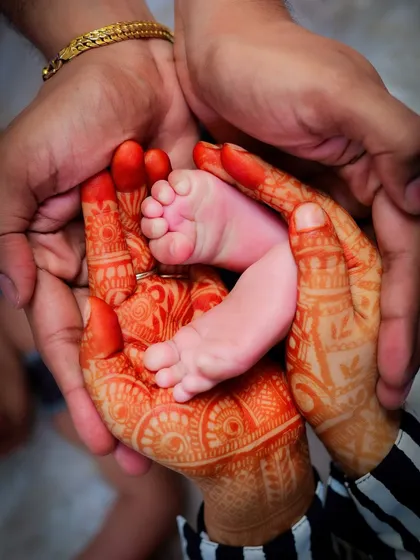 The contrast between the mother's intricate henna-adorned hands and her baby's tiny, perfect feet is just beautiful. This photo blends cultural tradition with the universal love for a new child.