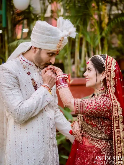 A classic, chivalrous gesture as the groom kisses the bride's hand. This shot captures a timeless expression of love and respect, highlighting their beautiful traditional wedding outfits.