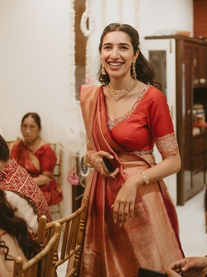 A candid shot of the bride, her red and gold saree a classic choice for the Mandap Muharat ceremony.