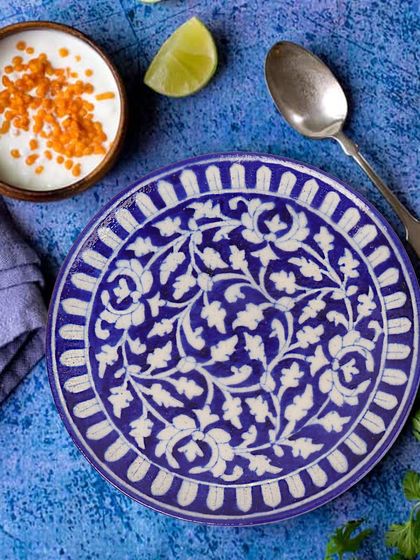 An overhead shot of a beautiful blue and white ceramic plate, styled with Indian food. This shows the plate in its intended use, making it more appealing to customers.