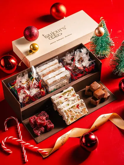 A wooden gift box filled with an assortment of Christmas confections, including nougat, fudge, and pate de fruit. This classic selection offers a taste of traditional European holiday sweets.