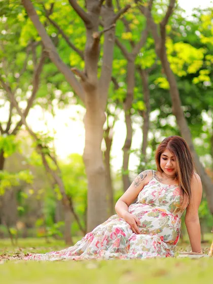 A relaxed and natural portrait of a mother-to-be sitting in the grass. The floral dress and the green surroundings create a fresh, springtime feel.