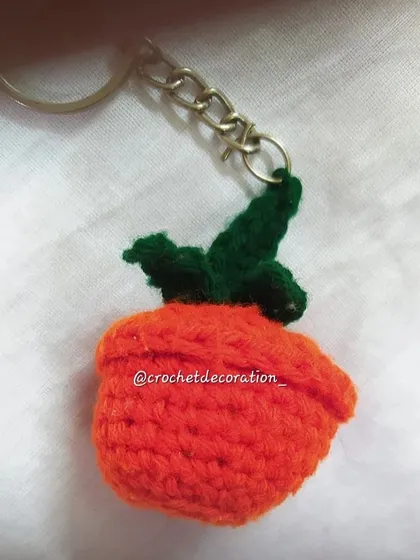 A small crochet plant keyring, shaped like a little pumpkin or a piece of fruit. This quirky and cute accessory adds a touch of nature to your everyday items.