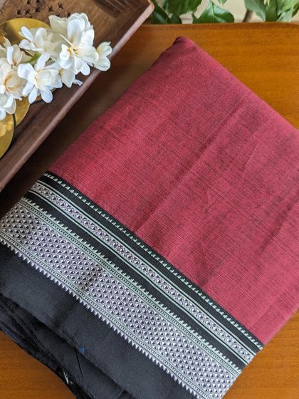 A close-up of a handloom Ilkal saree in a beautiful maroon with a black and silver traditional border. The cotton-viscose blend ensures a comfortable drape.