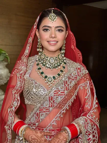 A full portrait of my stunning bride Ritika. The soft glam makeup perfectly balances the heavily embellished red lehenga and emerald jewelry.
