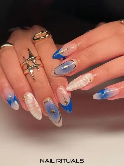 A closer look at our cosmic manicure. This image highlights the beautiful blend of blue aura, white marble, and gold star designs.