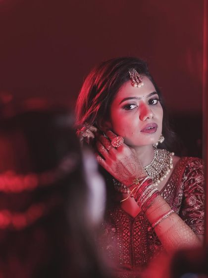 A dramatic, artistic shot of Sahana getting ready for her reception. The red lighting adds to the mood.
