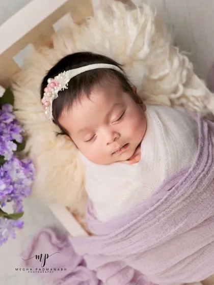 This angle shows the baby nestled in a white miniature bed.