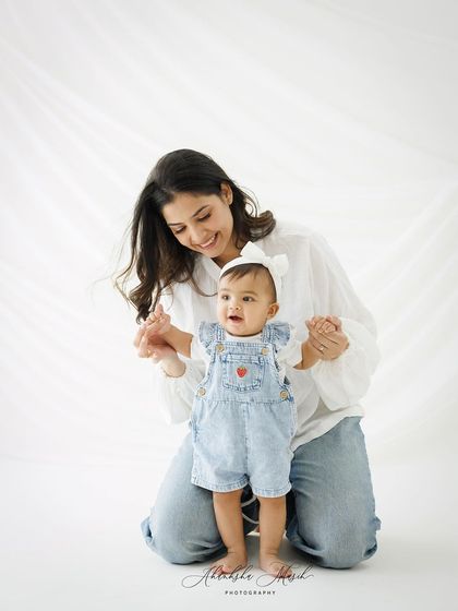 Helping her baby take her first steps. This is a milestone moment, full of pride and love, captured in a simple and beautiful way.