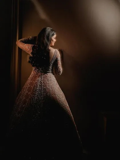A stunning solo portrait of the bride in a gorgeous gown. The dramatic side-lighting sculpts her form and creates a moody, artistic image that is both elegant and mysterious.