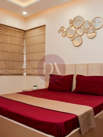This guest bedroom combines a rich red bedspread with a neutral headboard and a striking gold mirror art piece. The design is simple yet elegant, creating a warm and welcoming space for visitors.