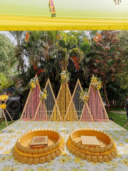 A closer look at a custom Haldi ceremony stage we designed. The setup features geometric wooden backdrops adorned with marigold and tuberose strings, perfectly complementing the traditional yellow theme.