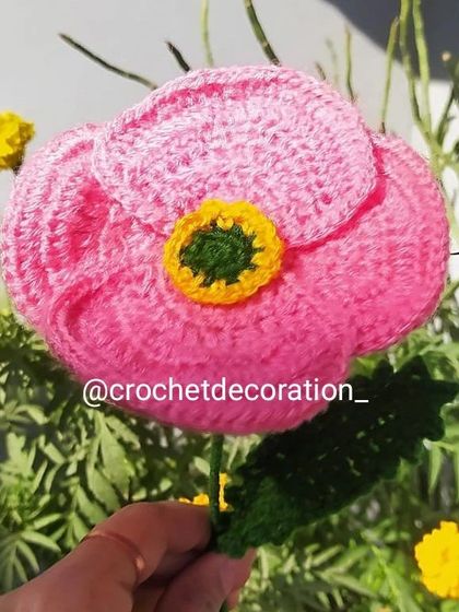 A single stem of a pink crochet poppy flower. The layered petals and detailed center make it a unique addition to any bouquet.