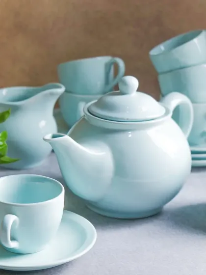 A serene, styled arrangement of a light blue ceramic tea set. The soft lighting and simple composition give the image a calm and inviting feel, perfect for home goods.