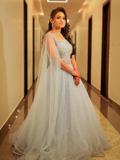 A full-length portrait of a model in a flowing, light blue gown, perfect for an evening wear or pre-wedding look.