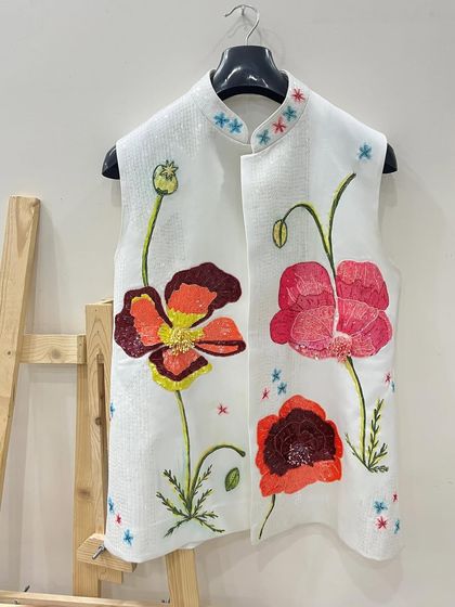 The finished poppy vest on an easel. The combination of painting and beadwork makes this piece truly special and textured.