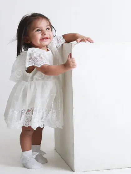 A joyful smile from a little girl who has just learned to stand. A proud milestone moment captured in a simple, elegant style.