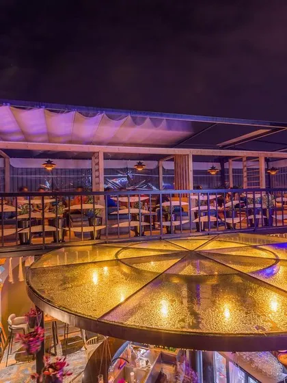 The glowing central bar structure at night, seen from the upper seating deck. The design creates multiple levels and zones, offering varied experiences within the same venue.