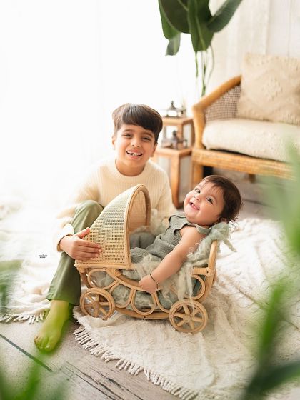 Big brother proudly showing off his baby sibling in a cute little wagon.