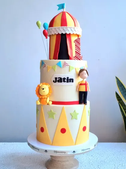 A full view of the three-tiered carnival cake, showing the clean fondant work and character placement.