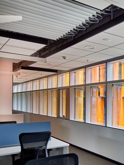Inside the Infosys office, the colorful facade fins create a pleasant, diffused light. The design optimizes the floorplate for work areas, with exposed ceilings and efficient layouts that ensure both spatial generosity and clarity in circulation.