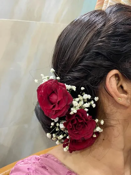 A classic low bun adorned with red roses and baby's breath. This is an elegant and sophisticated choice for any occasion.