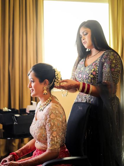 A makeup artist puts the finishing touches on the bride's hair, a key behind-the-scenes moment.