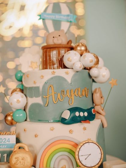 A close-up of the incredible travel-themed cake, adorned with a hot air balloon, a plane, a calendar, and a clock.