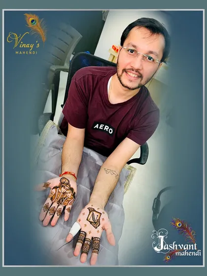 This groom opted for a mix of styles. One hand features a Radha-Krishna portrait, while the other has a bold initial 'N' for a personalized and meaningful design.