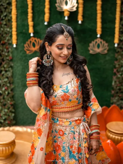 The bride looks radiant in her floral lehenga, her smile capturing the excitement of the Haldi function.