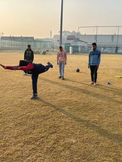 Balance and stability are key components of a cricketer's fitness. This player is performing a dynamic balance exercise, which is crucial for both batting and bowling.