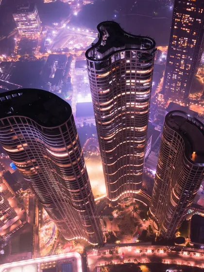 A closer aerial shot of the Lodha Park towers. This perspective highlights the curves and lines of modern architecture, lit up against the night sky.
