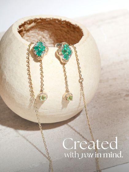A close-up of the Green Meadow earrings, featuring emerald clusters and peridot drops on a delicate chain. Each piece is created with you in mind.