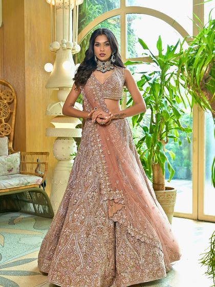 A full-length view of this gorgeous reception lehenga. The makeup is designed to complement the dusty rose color and intricate embroidery of the outfit.
