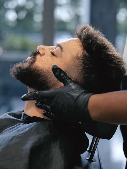 A client relaxing while our expert barber provides a precise beard trim and shaping service.