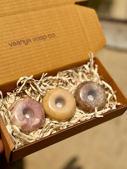 A still shot of our Donut Soap Box, highlighting the different textures and colors of the Sweet Rose, Haldi Doodh, and Vanilla Scrub soaps.