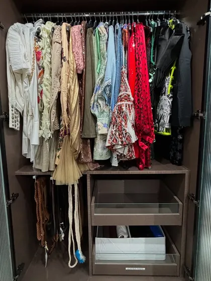 This closet with fluted glass doors contains a mix of hanging party wear and drawers for other items.