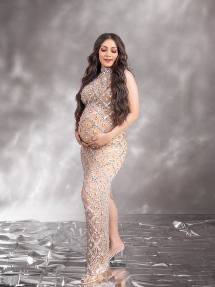 A serene and glowing portrait, with the mom-to-be gently cradling her bump in this dazzling gown.