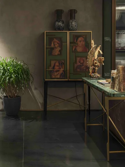 A custom-designed cabinet with photographic portraits sits next to a green aventurine console table in the Bammi Residence living room. This vignette demonstrates our approach to creating personalized, story-rich spaces.