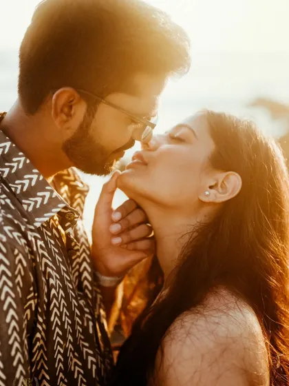 A sun-flared, intimate close-up of a couple about to kiss on a Goan beach. We use natural light to create dreamy, romantic portraits that feel warm and authentic.