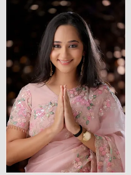A welcoming and graceful pose in a delicate pink saree. This image radiates warmth and is perfect for festive or family-oriented themes.