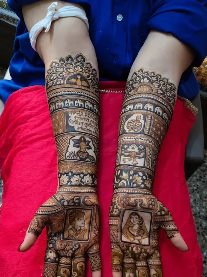 This personalized mehandi includes portraits of the couple, religious symbols like the kalash, and a Sanskrit shloka, blending tradition with personal touches.