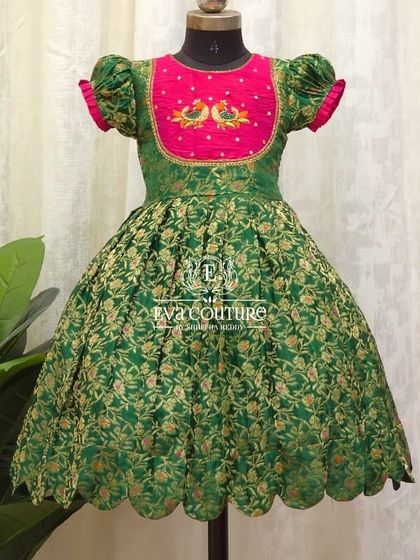 A similar Banarasi frock design with puff sleeves and a scalloped hem. The yoke features delicate peacock embroidery.