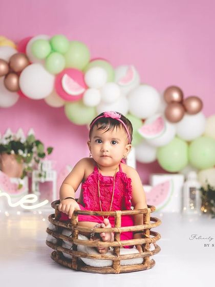 A wide shot of the watermelon-themed first birthday setup, showing the beautiful balloon arch and fun props.