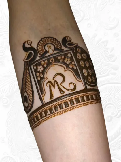 The first step of a bridal armlet, featuring the couple's initials inside a jharokha.