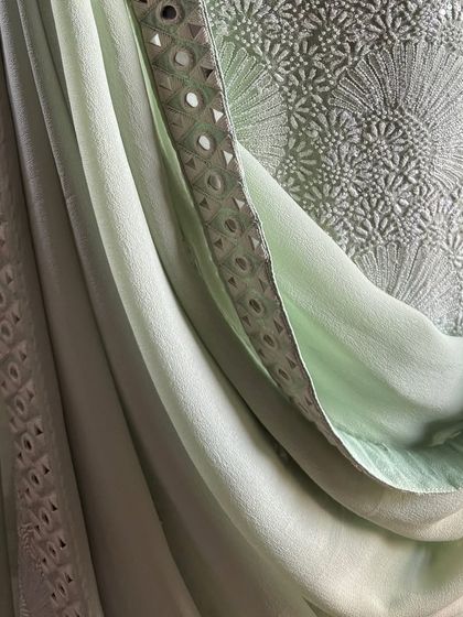 A detail shot of the draped dupatta, showing its mirrorwork border and the sheer texture of the fabric.